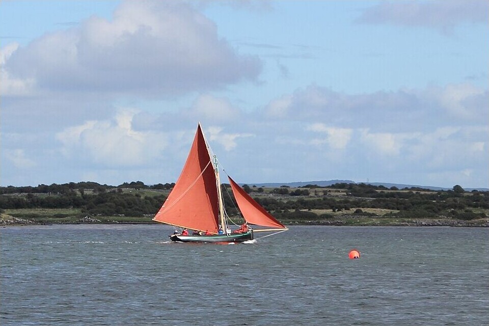 The Galway Hooker: The Red-Sailed Boat That Defined Galway Bay Traditional Galway Hooker sailing on Galway Bay with rust-red sails