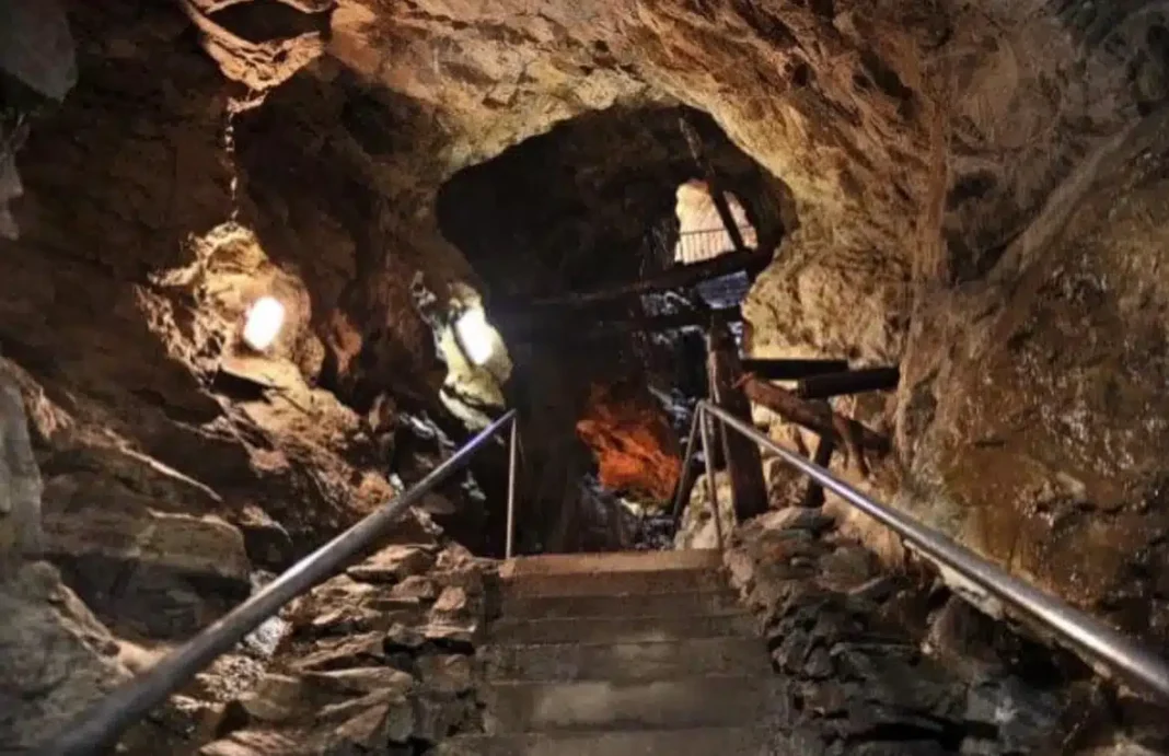 Stone steps and handrails leading into an illuminated underground chamber at Glengowla Mines